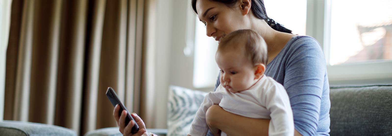 Mother using a smartphone while holding a baby