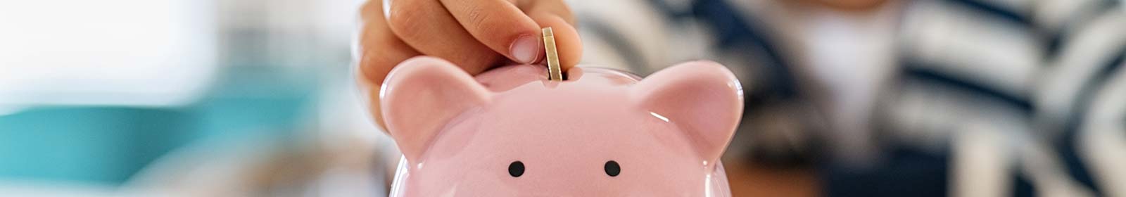 Kid dropping a coin in a piggy bank