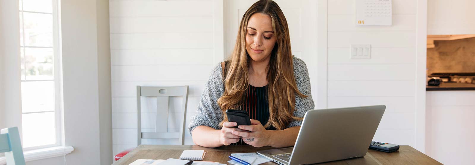 Lady at home using a smartphone and laptop computer